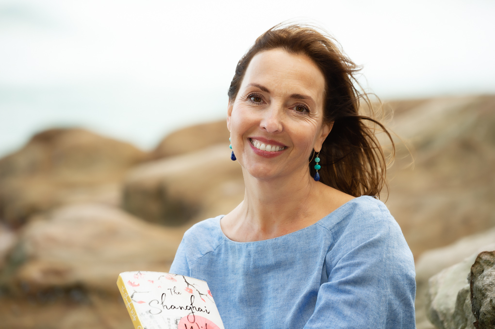 A lifestyle portrait of Australian author Emma Harcourt holding her new novel at Bondi Beach. Emma has written a new novel called Shanghai Wife, inspired by her Aussie grandparents who lived in 1920s Shanghai.