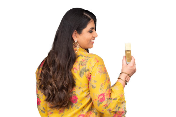 Minal Singhal from Niyam Wellness holding hair oil in a product branding photograph